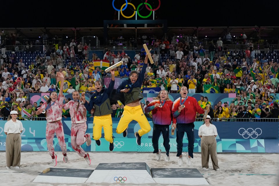 a group of people are jumping in the air in front of the olympic rings