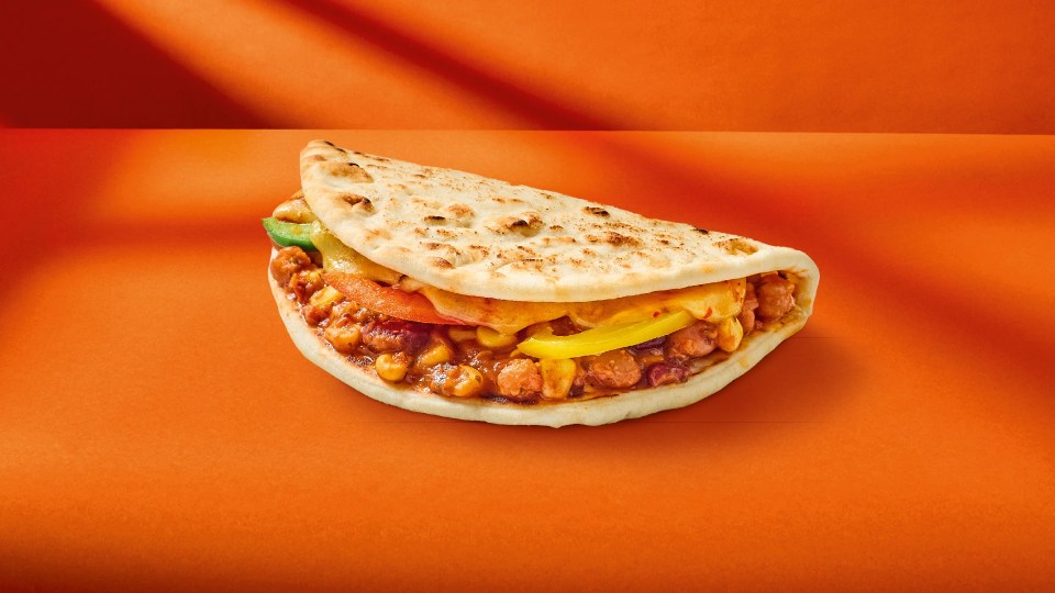 a sandwich with chickpeas and cheese on an orange surface