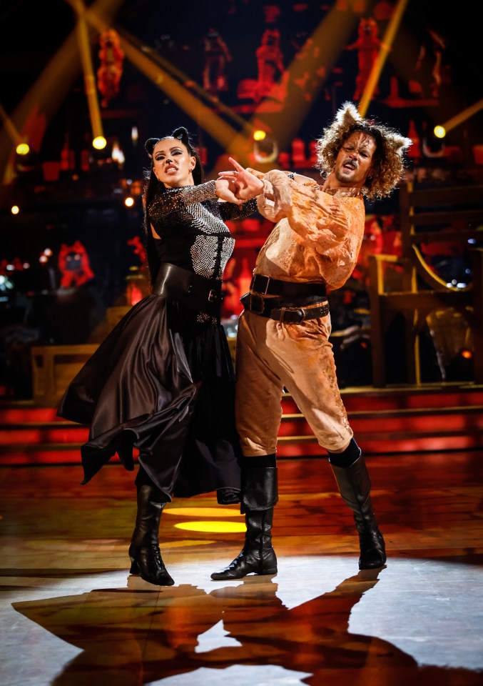 a man in a cat costume is dancing with a woman in a black dress