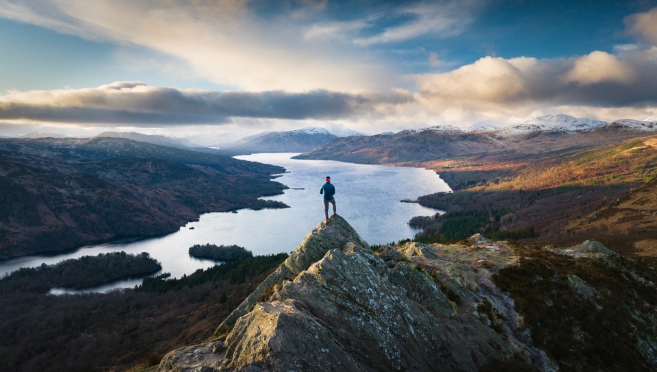 A hiker on the summit of Ben A'an in the Scottish Highlands