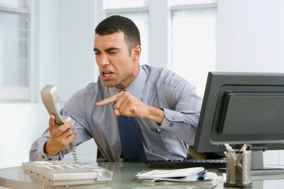 a man sitting at a desk talking on a telephone