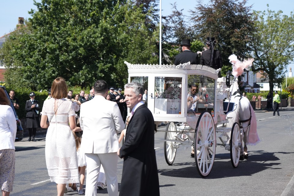 a white horse drawn carriage is being pulled down the street