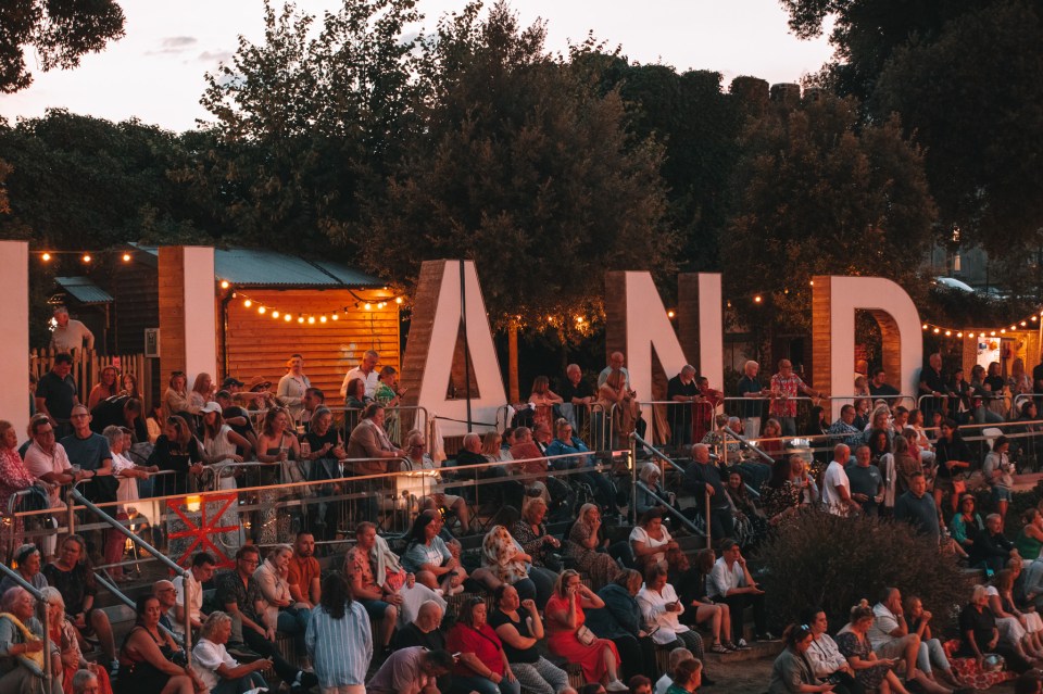 a crowd of people sit in front of a sign that says island