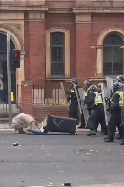 a group of police officers with shields and a trash can with the letter v on it