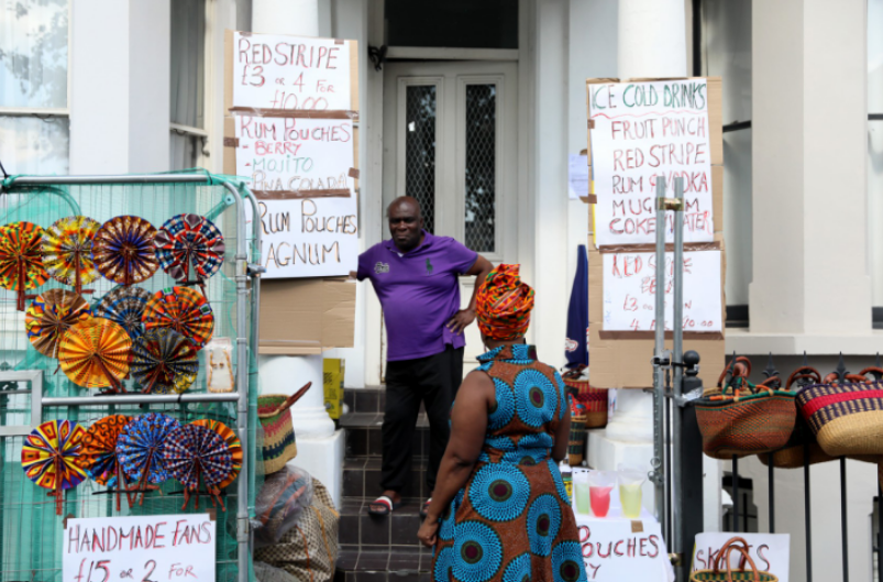 A man stands outside a house selling drinks at Notting Hill Carnival