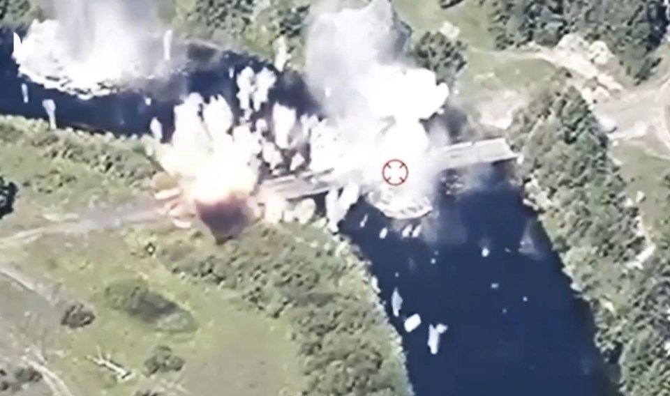 an aerial view of a bridge exploding in the middle of a river .