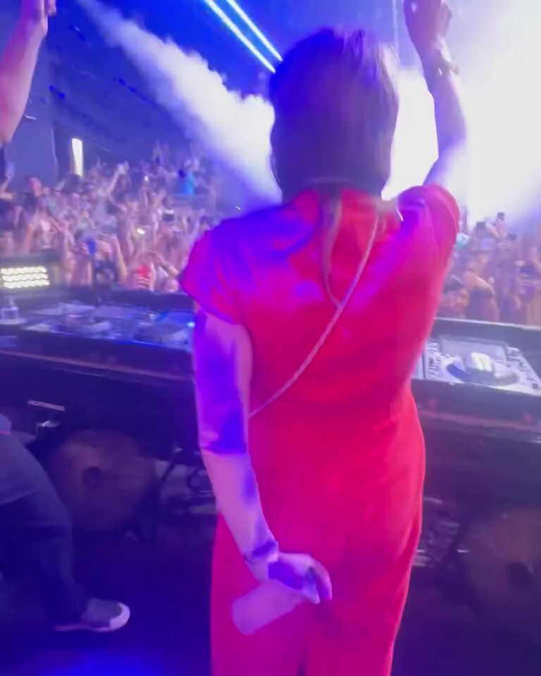 a woman in a red dress is dancing in front of a crowd