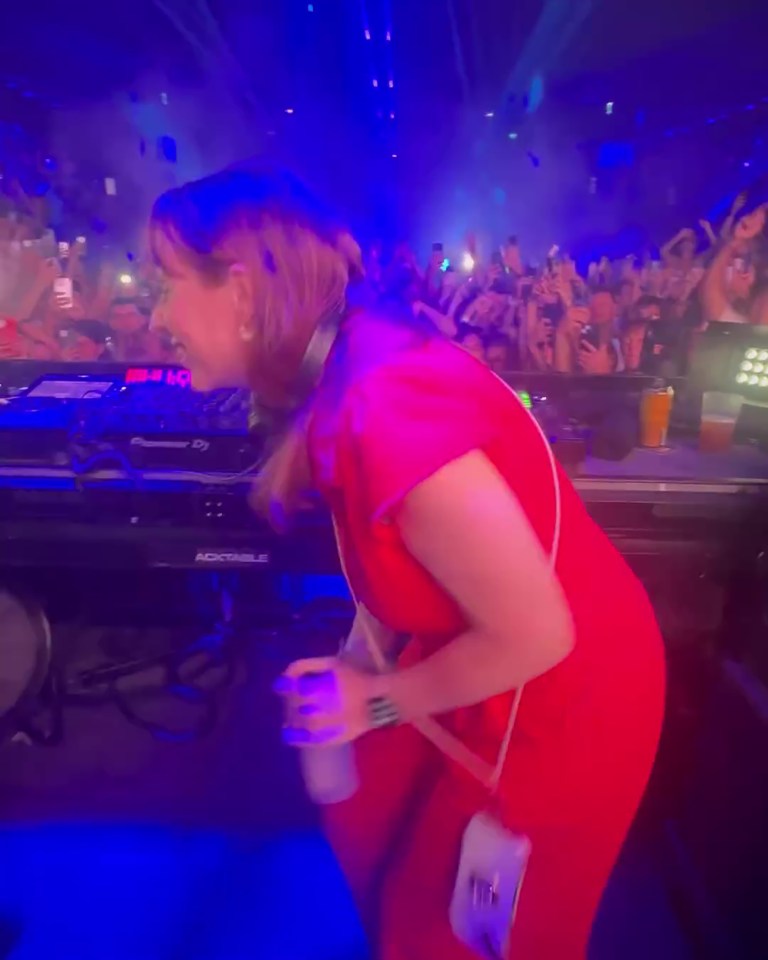 a woman in a red dress stands in front of a pioneer dj machine