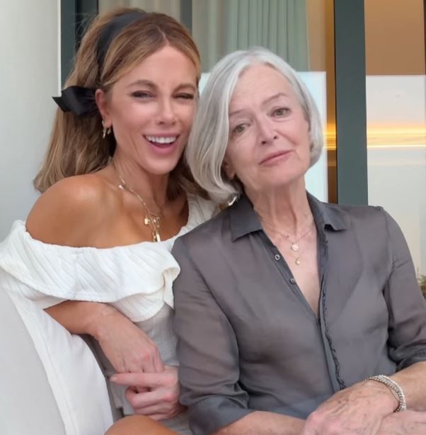 a woman in a white off the shoulder top sits next to an older woman in a grey shirt