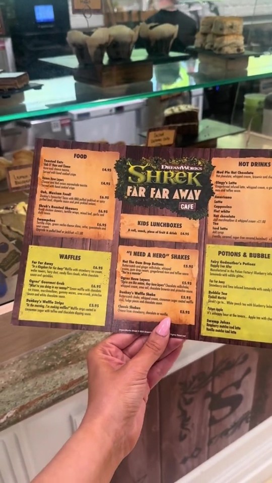 a person holding a shrek far far away cafe menu