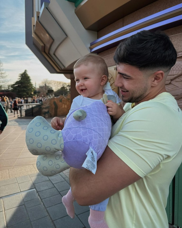 a man holding a baby with a label that says ' disney ' on it