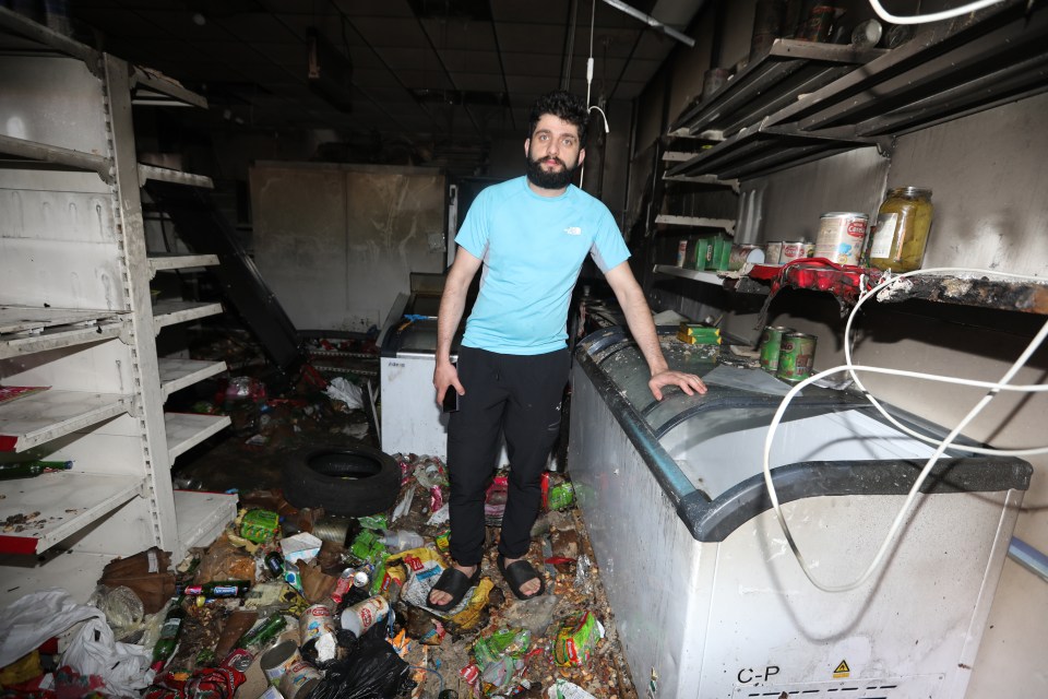 a man in a blue north face shirt stands in a messy room