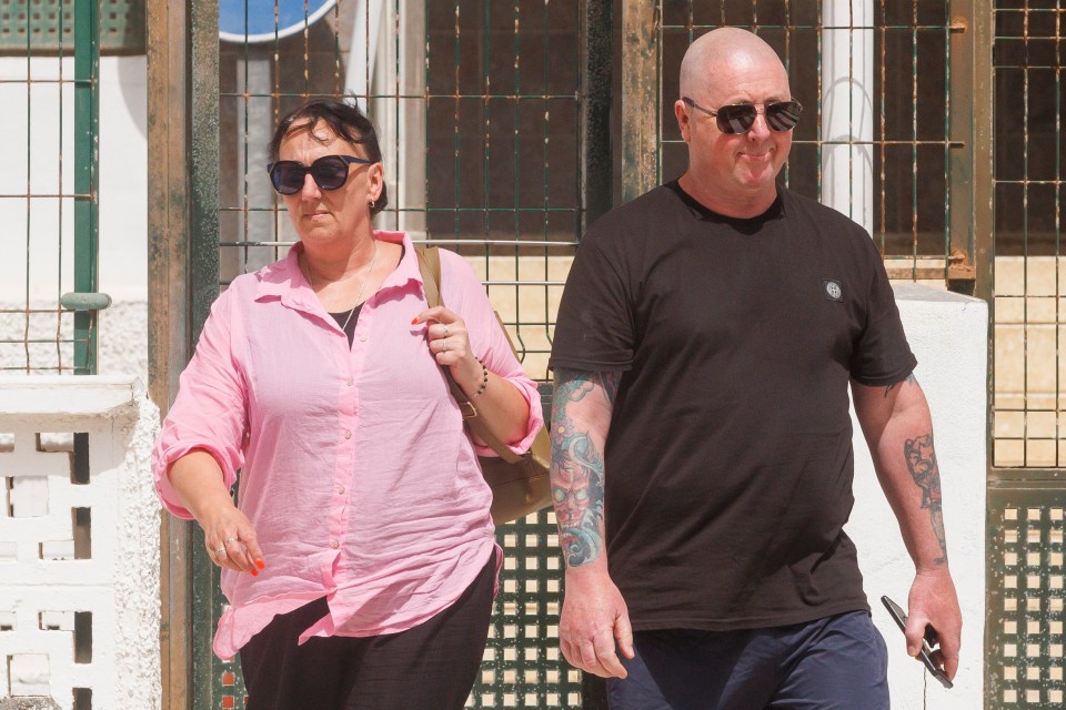 a woman in a pink shirt is walking next to a man in a black shirt