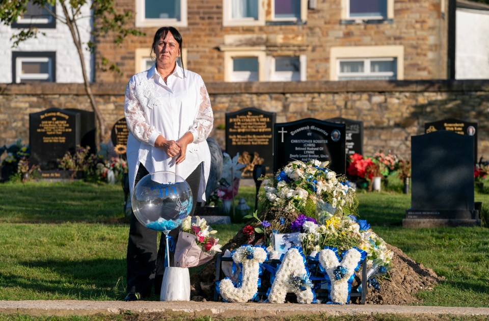 a woman stands in front of a grave with the name jay on it