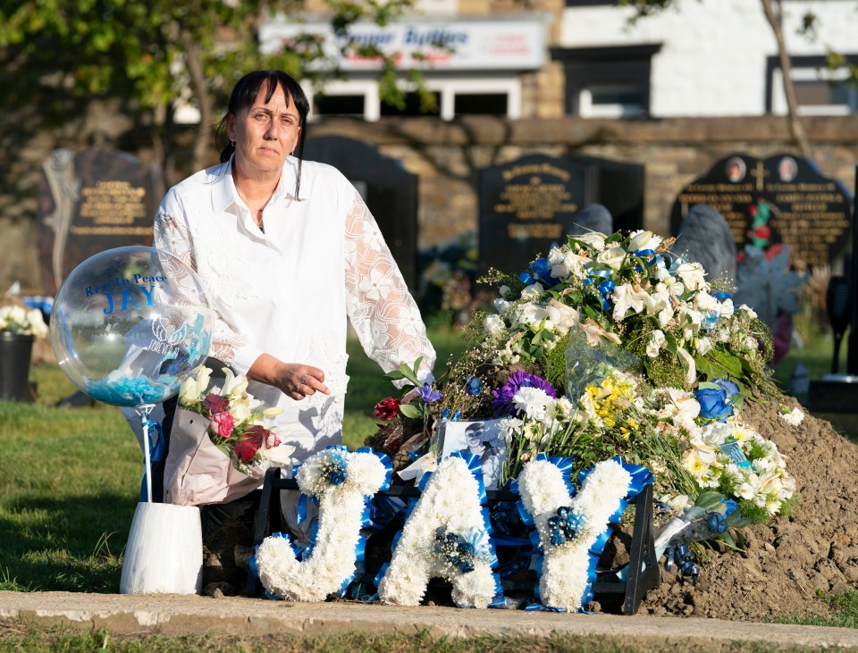 a woman kneeling in front of a grave with flowers and letters that say jay