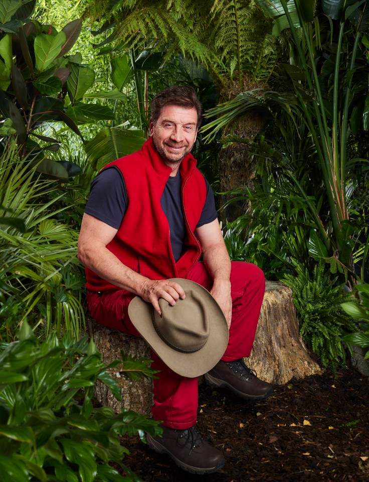 a man in a red vest is sitting on a rock in the jungle