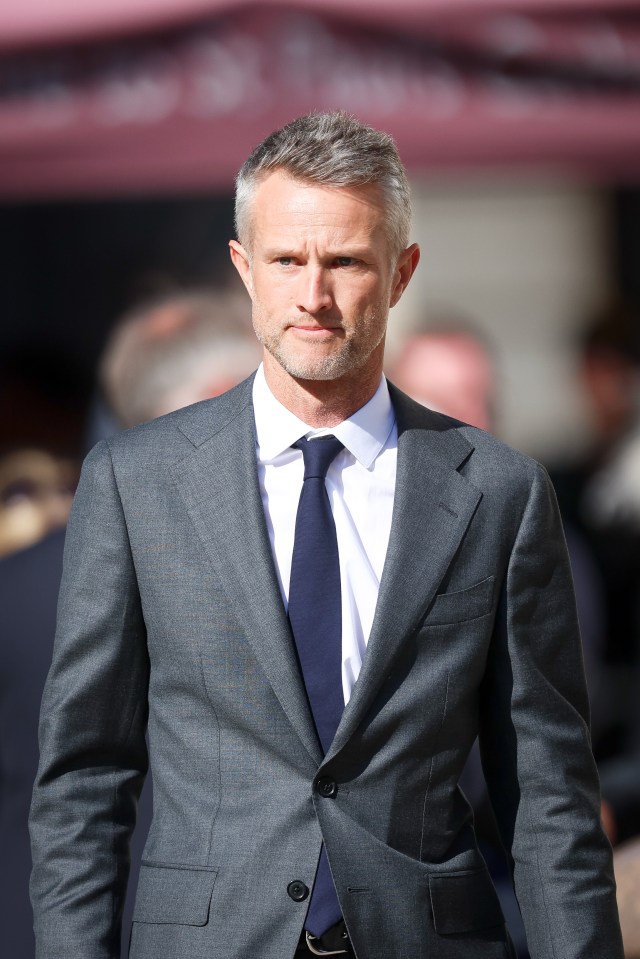 a man in a suit and tie stands in front of a pink awning