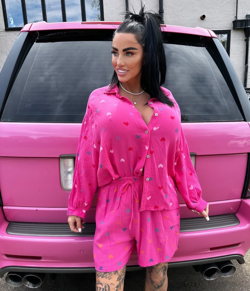 a woman in a pink shirt and shorts stands in front of a pink car