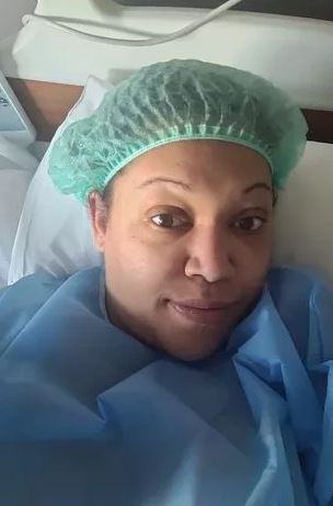 a woman is laying in a hospital bed wearing a surgical cap and gown .