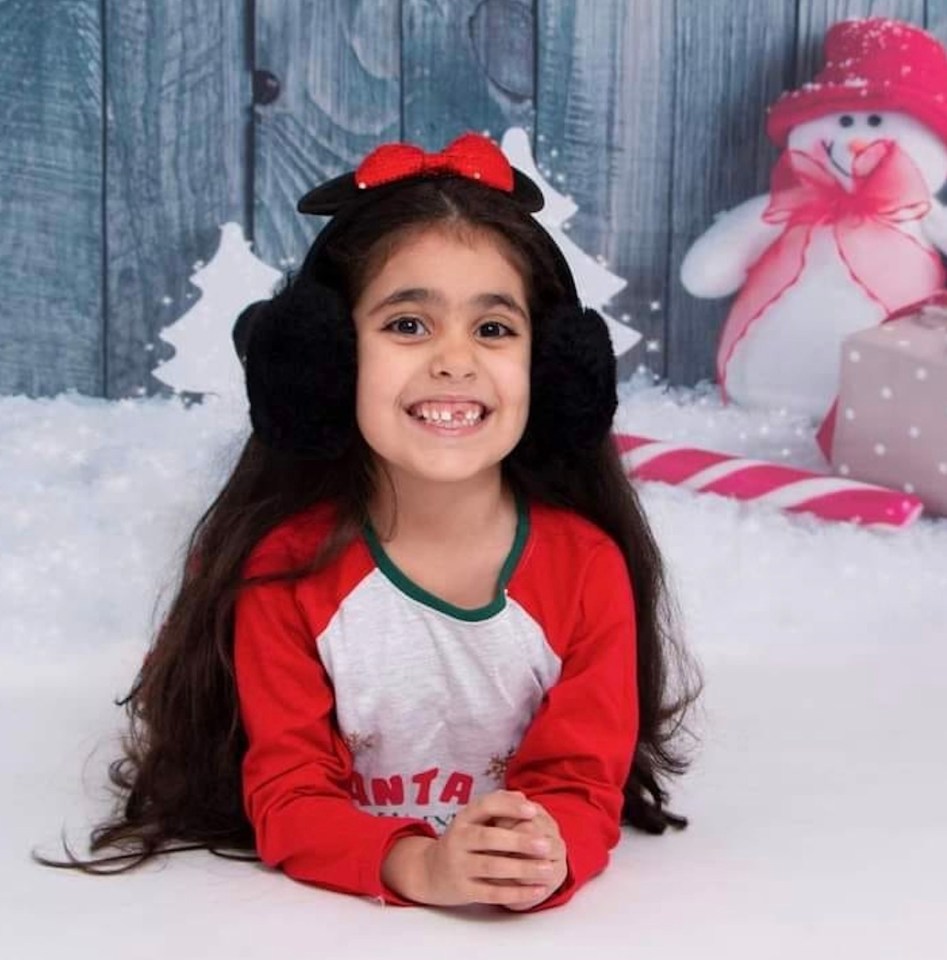 a little girl wearing ear muffs and a santa shirt