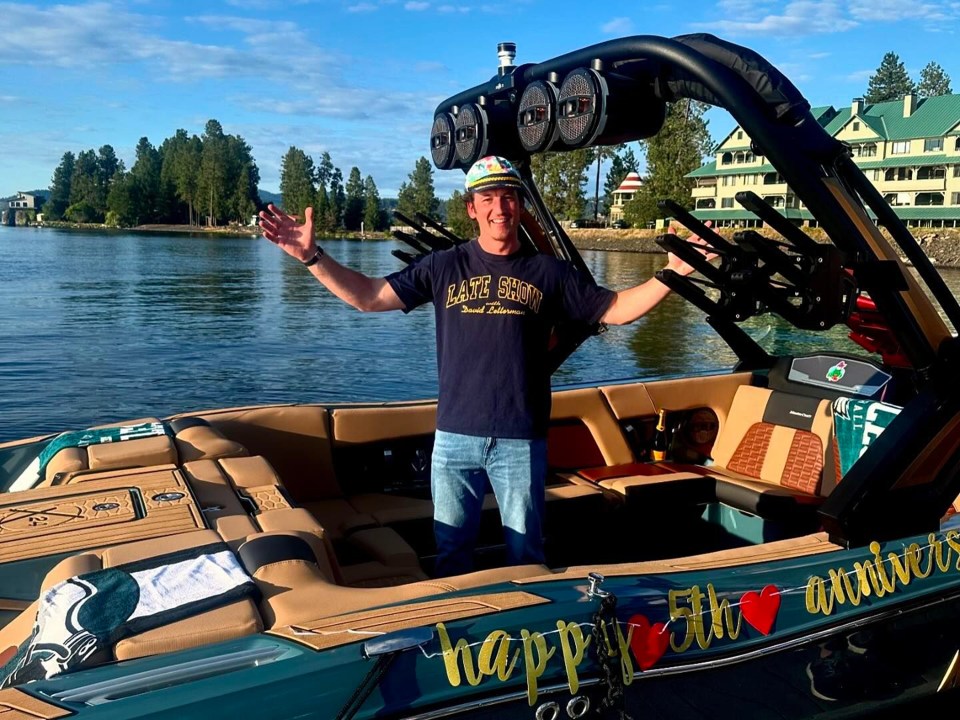 a man stands in front of a boat that says happy 5th anniversary