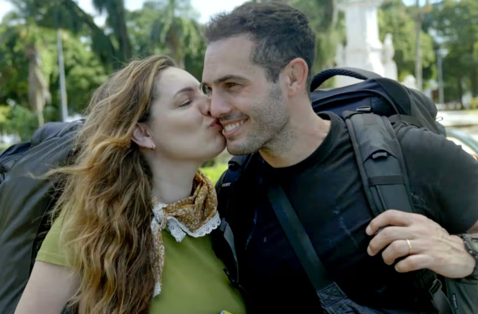 a woman kisses a man on the cheek with a black backpack