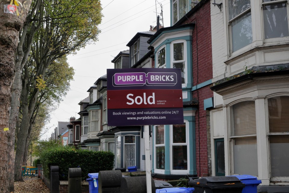 a purple bricks sold sign in front of a row of houses