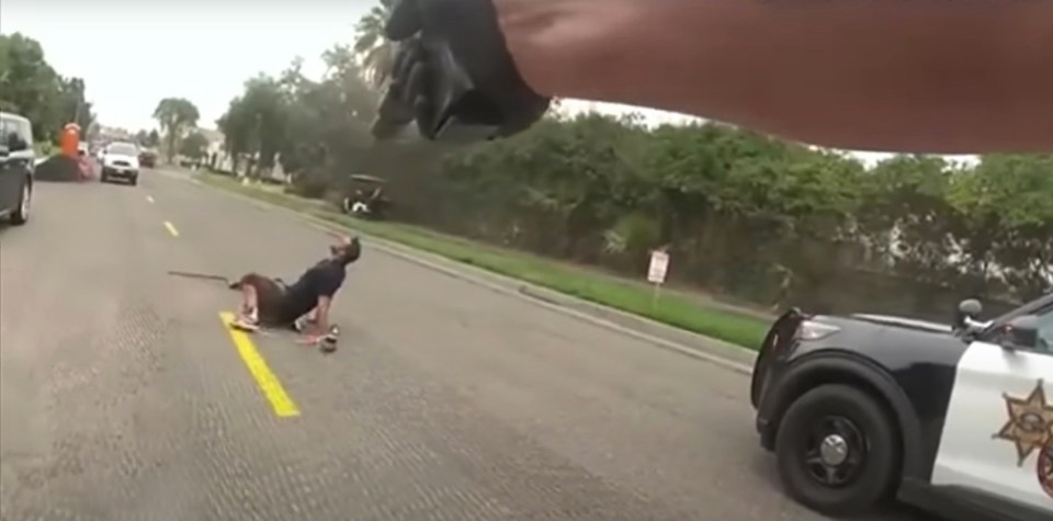 a man is laying on the side of the road next to a police car