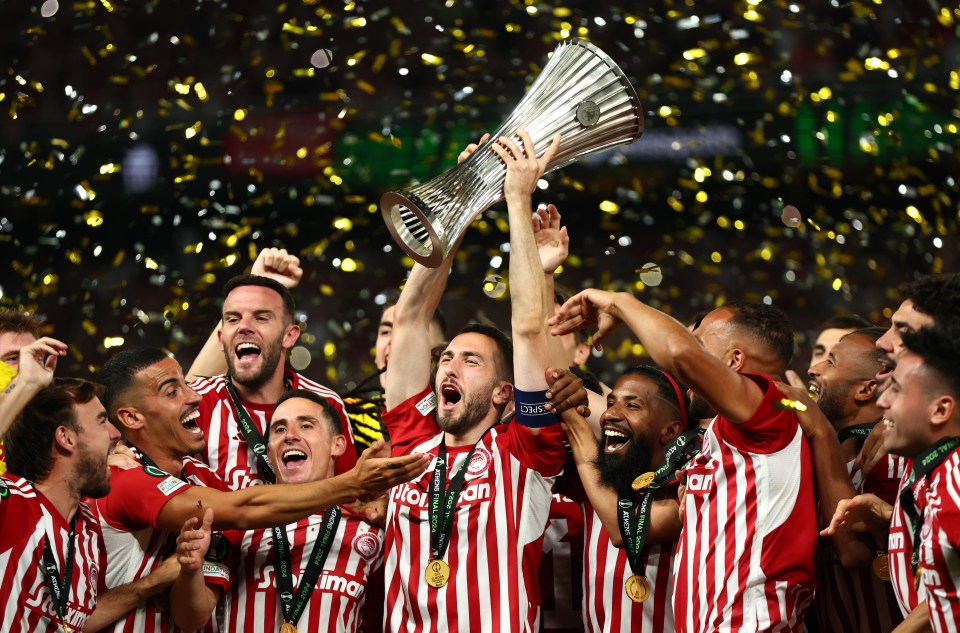 a group of soccer players celebrate with a trophy in the air