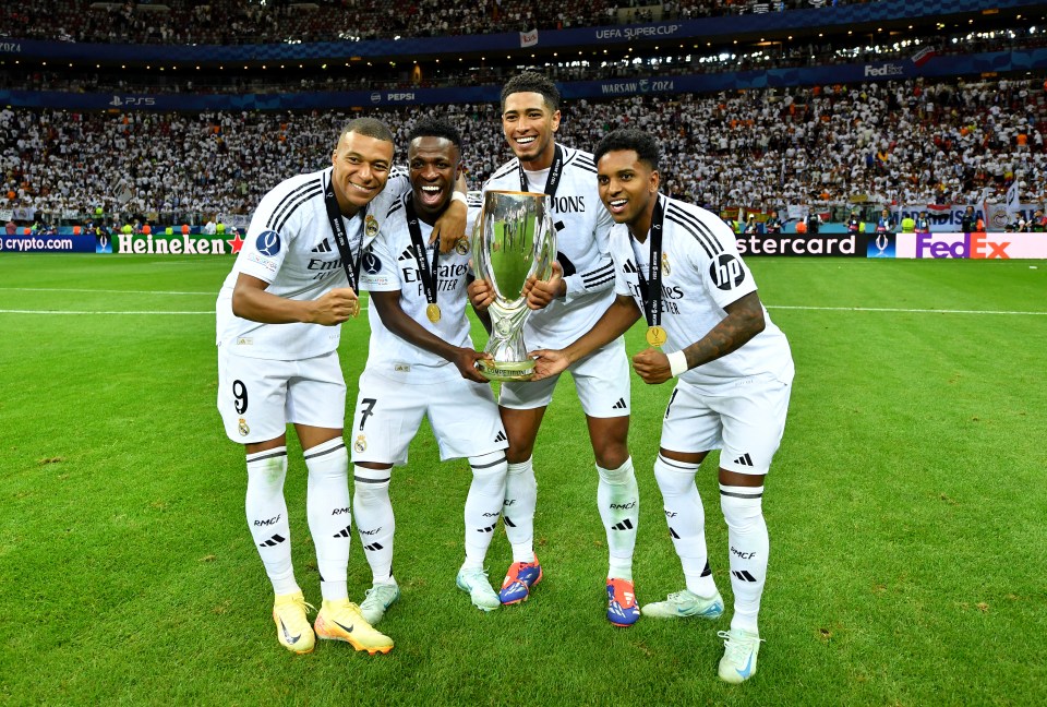 a group of soccer players holding a trophy in front of a heineken ad