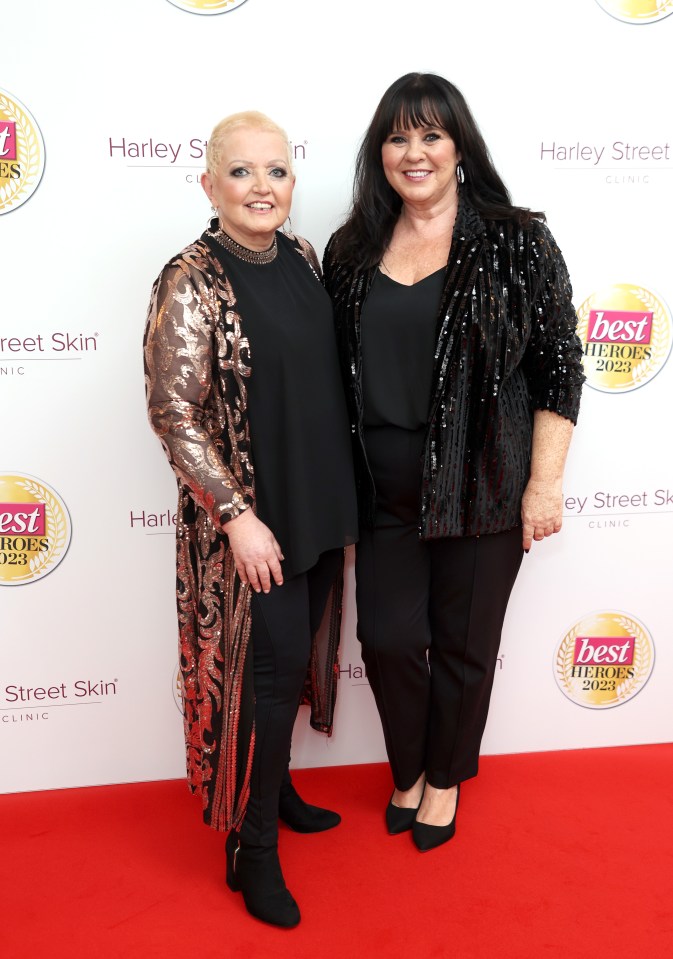 two women stand on a red carpet in front of a sign that says best heroes 2021