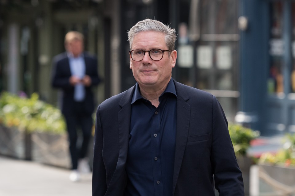 a man wearing glasses and a suit walks down a street