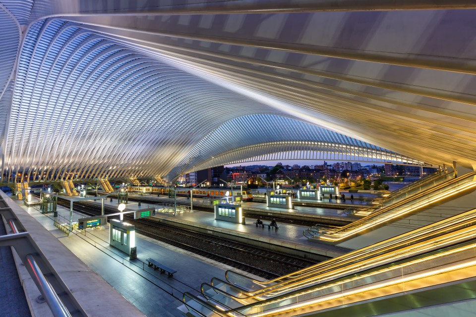 a train station with a curved ceiling and escalators