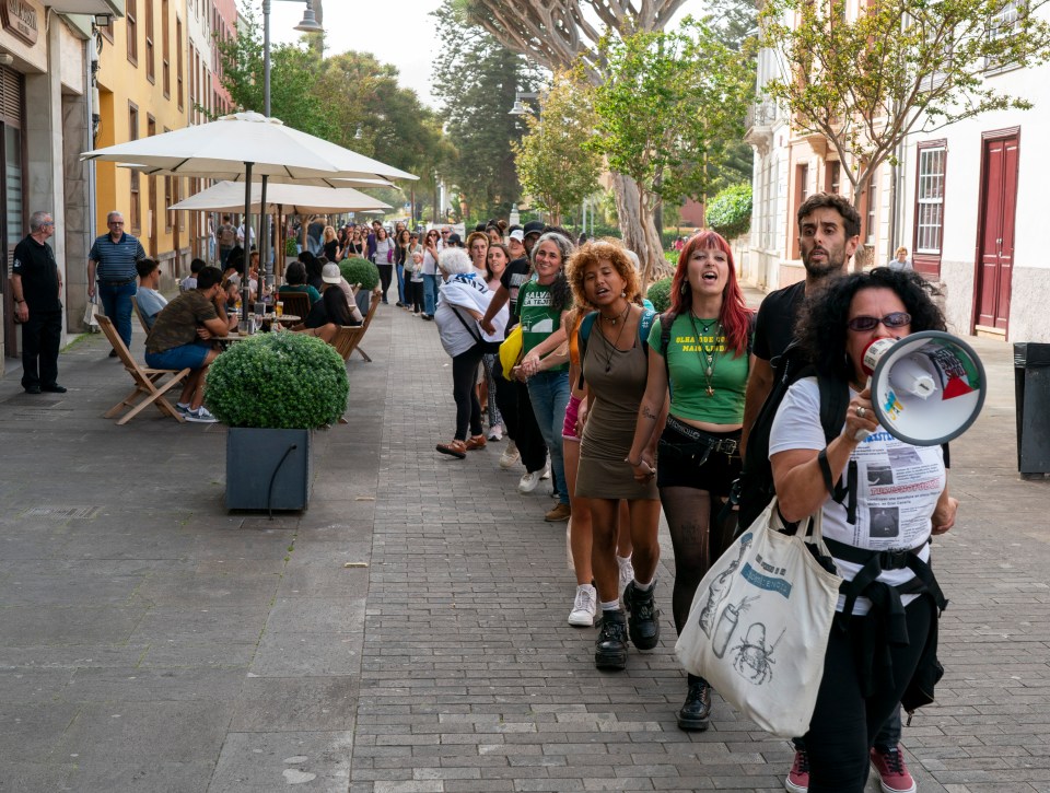 a group of people walking down a street with one woman holding a megaphone