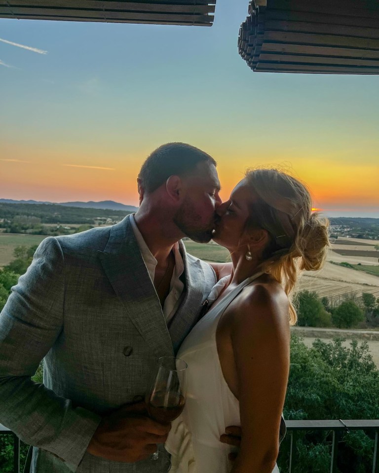 a man and woman kissing with a sunset in the background