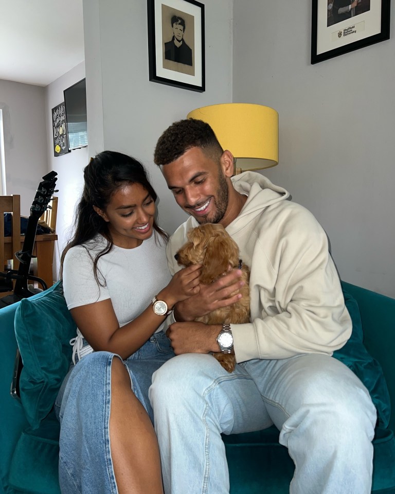 a man and a woman are sitting on a couch holding a dog