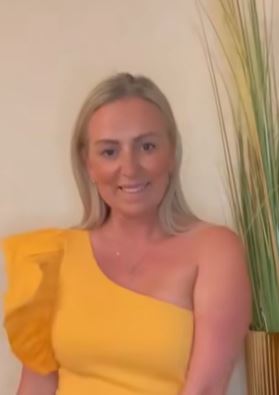 the woman is wearing a yellow one shoulder dress and smiling .