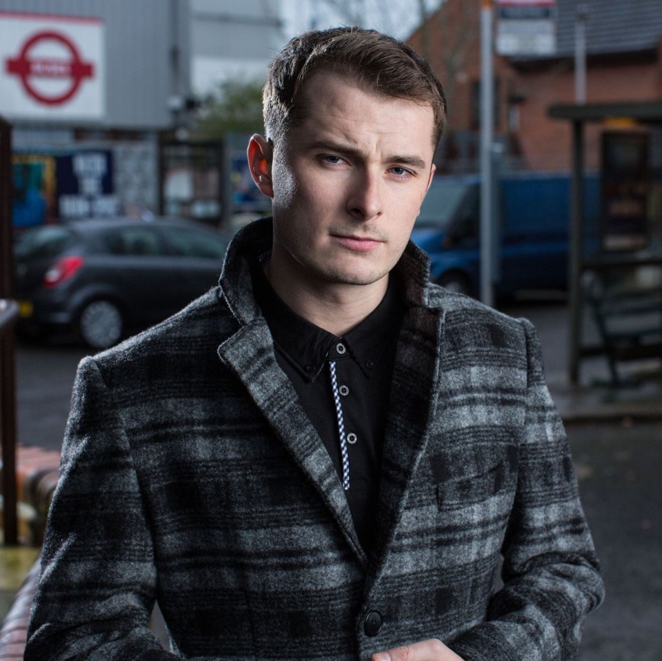 a man in a plaid coat stands in front of a subway sign