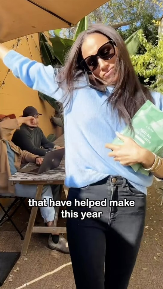 a woman in a blue sweater is holding a bag that says " that have helped make this year "