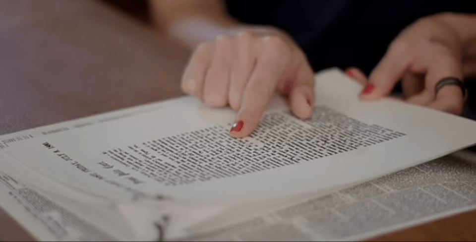 a woman with red nail polish is reading a book