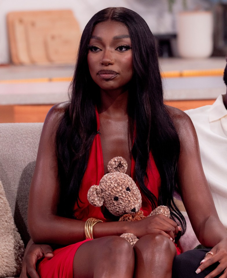 a woman in a red dress is holding a teddy bear