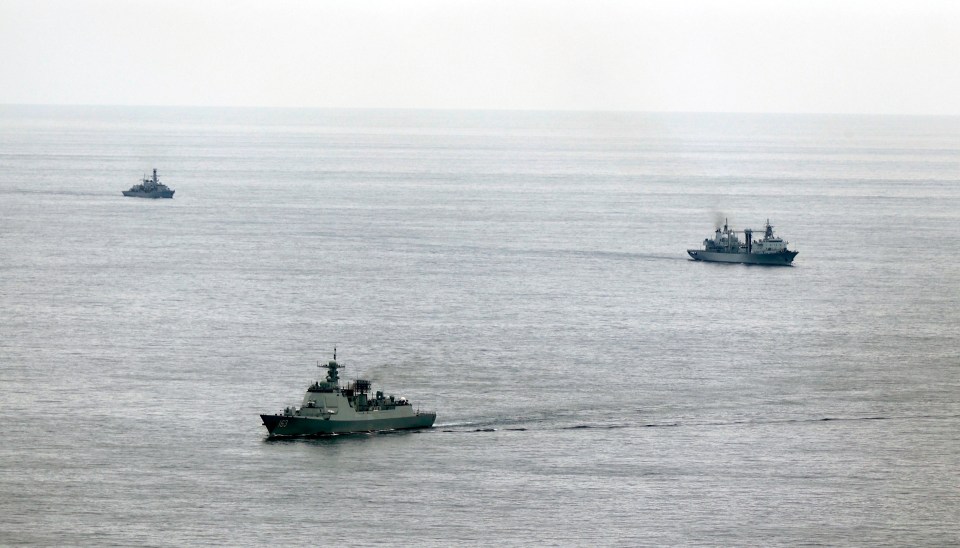 three ships are floating in the ocean one of which is a military ship