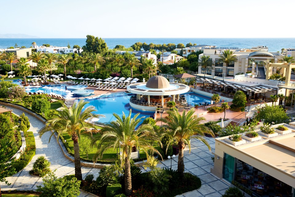 a large swimming pool surrounded by palm trees and umbrellas