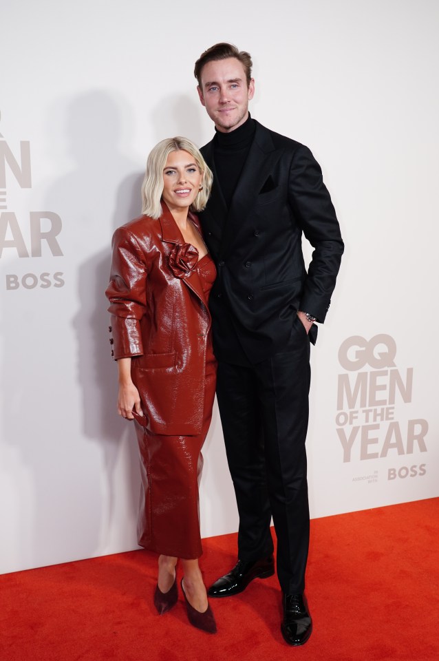 a man and a woman pose on a red carpet that says gq men of the year