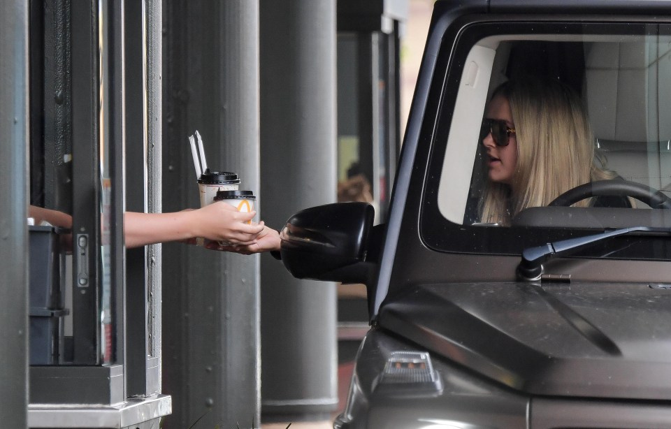 a woman getting a cup of coffee from a mcdonald 's drive thru