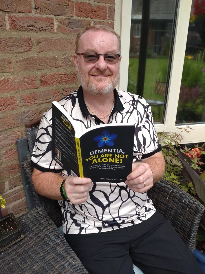 a man is holding a book titled dementia you 're not alone