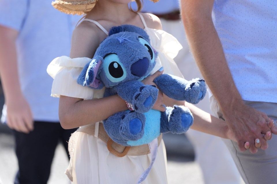 a little girl is holding a stuffed animal that says stitch