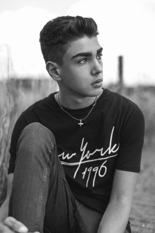 a black and white photo of a young man wearing a new york 1996 t-shirt