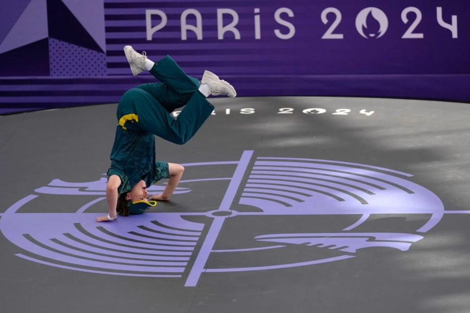 a person doing a handstand in front of a sign that says paris 2024