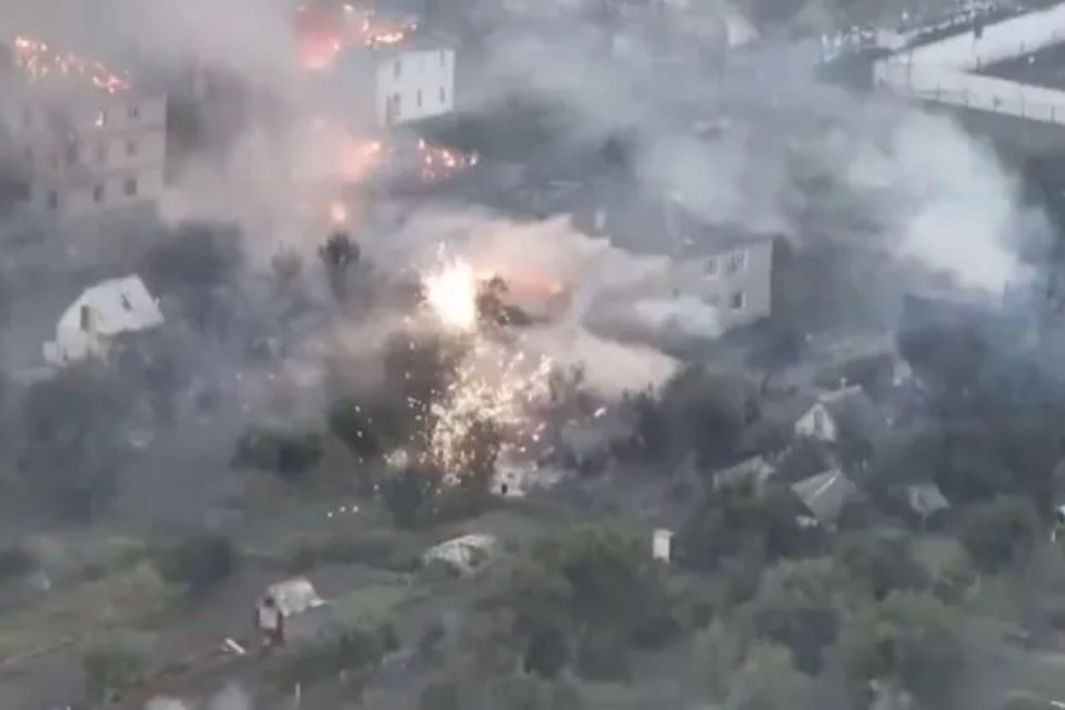 an aerial view of a fire in a village with a lot of smoke coming out of it .